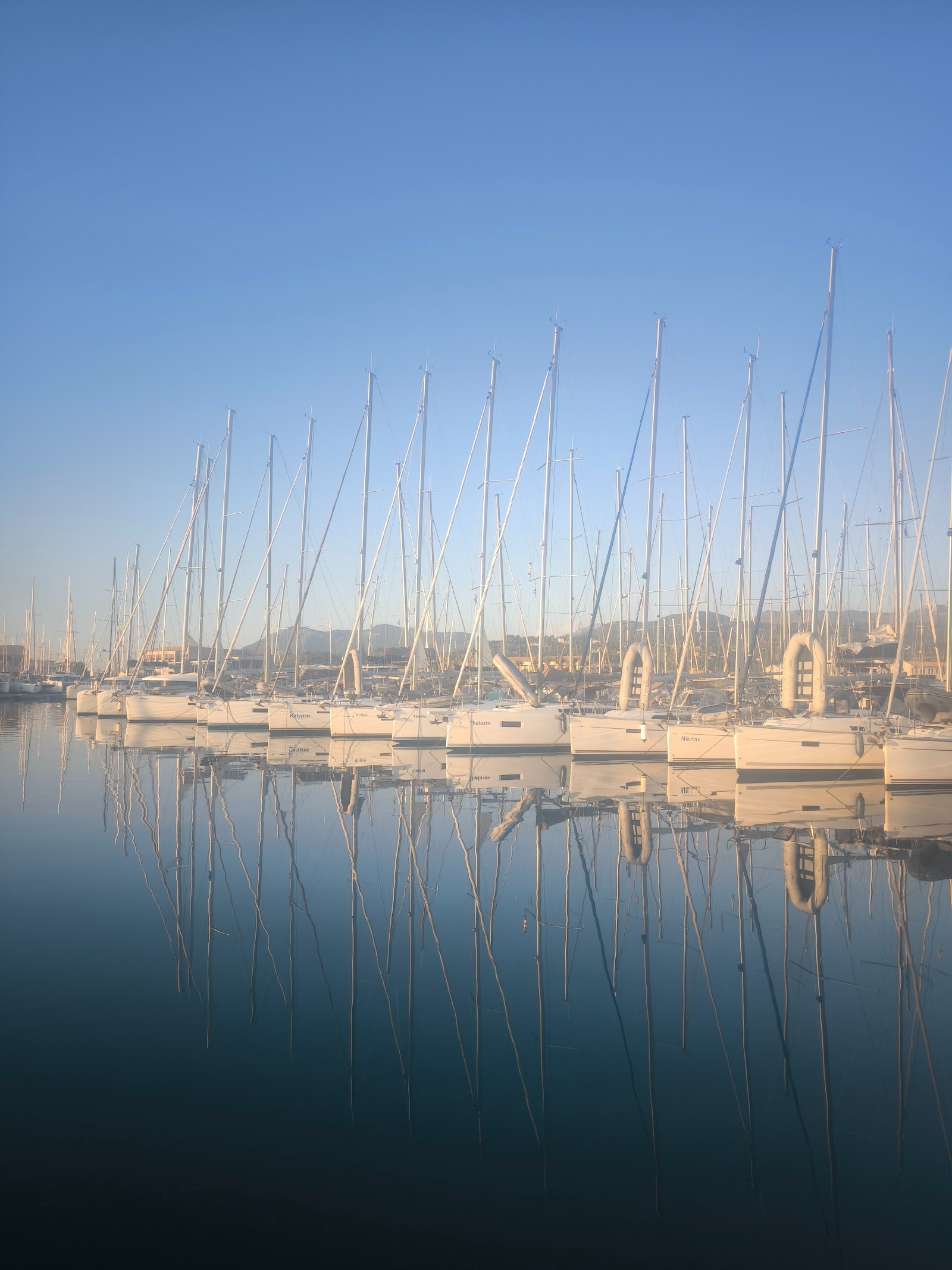 Sailboat masts mirrored in the calm morning water of Lefkada marina, Greece